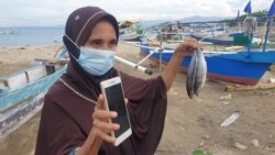 Ibu Mardia Djaelangkara, warga Talise, memperlihatkan ikan katombo yang dibeli dari nelayan untuk dijual kembali menggunakan platform media sosial. Sabtu, 19 Desember 2020. (Foto: VOA/Yoanes Litha)