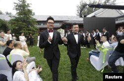 FILE - Gino, left, and Ling Jueding leave after their wedding at a park in Beijing, June 27, 2015. The gay couple had to change the venue for their ceremony nearly 10 times because of intervention from local police. Same-sex marriage is illegal in China, but holding the wedding to mark their 2½-year relationship was a personal wish for the couple, according to Gino.