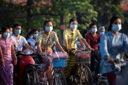 FILE - People wearing protective face masks ride bikes on a street, amid the outbreak of the coronavirus disease (COVID-19), in Yangon, Myanmar, December 7, 2020.
