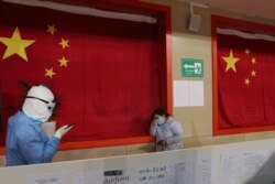 A medical worker in protective suit comforts a patient inside a sports stadium which has been converted into a makeshift hospital to treat patients of the novel coronavirus, in Wuhan, Hubei province, China February 27, 2020.