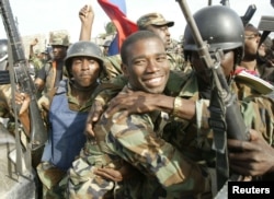 FILE - Haitian National Revolutionary Liberation Front Commander-in-Chief, Guy Philippe, hugs other soldiers, Feb. 22, 2004.