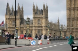 FILE - Pedestrians walk by newly installed barriers on Westminster Bridge in London, June 5, 2017.