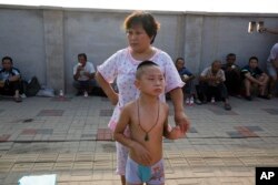 A woman and a child wait to return home near the site of an explosion in northeastern China's Tianjin municipality, Aug. 13, 2015.