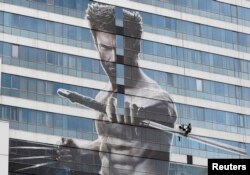 FILE - A worker installs a poster of Hugh Jackman in the new movie "The Wolverine" on a building in Bangkok July 9, 2013.