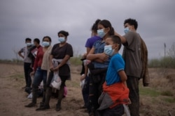 FILE - About a dozen asylum seeking unaccompanied minors from Central America are separated from other migrants by U.S. Border Patrol agents after crossing the Rio Grande river into the United States from Mexico on a raft in Penitas, Texas, U.S., March 14, 2021.
