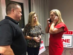 Supporters stand with construction executive Marjorie Taylor Greene, right, as she's on the phone, late Tuesday, Aug. 11, 2020, in Rome, Ga.
