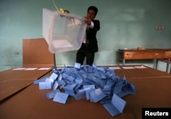 FILE - An Afghan election official empties a ballot box for counting at the end of polling in Herat Province, April 5, 2014.