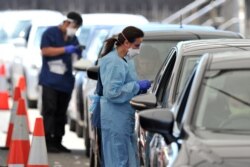 Pejabat kesehatan mengumpulkan tes swab COVID-19 di drive-through di Pantai Bondi di Sydney pada 15 Desember 2021, ketika kluster Omicron dan Delta yang berkembang pesat membawa lebih dari 2.700 kasus baru secara nasional. (Foto: AFP/Mohammad Farooq)