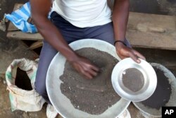 FILE - A Congolese miner sifts through ground rocks to separate out the cassiterite, the main ore that’s processed into tin, in the town of Nyabibwe, eastern Congo, a once bustling outpost fueled by artisanal cassiterite mining, Aug. 16, 2012.