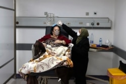 In this Friday, Jan. 22, 2021 file photo, a woman combs the hair of her sister, a COVID-19 patient, at the intensive care unit of the Rafik Hariri University Hospital in Beirut, Lebanon. (AP Photo/Bilal Hussein, file)