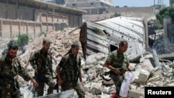 FILE - Forces loyal to Syria's President Bashar al-Assad walk with their weapons past rubble after they advanced on the southern side of the Castello road in Aleppo, Syria, in this handout picture provided by SANA on July 28, 2016.