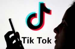 A person holds a smartphone as Tik Tok logo is displayed behind in this picture illustration taken November 7, 2019.
