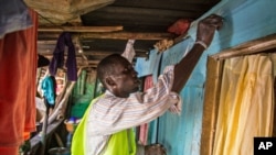 FILE - A health worker marks a home with chalk to identify that it has been visited, as they distribute bars of soap and information about Ebola in Freetown, Sierra Leone, Sept. 20, 2014.