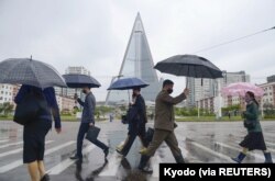 Orang-orang mengenakan masker berjalan di tengah kekhawatiran atas pandemi COVID-19 di Pyongyang, Korea Utara, 15 Mei 2020. ( Kyodo via REUTERS)