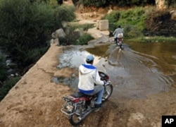 Syrian men cross the Kabir River into Syria from Wadi Khaled, Lebanon, October 13, 2011.