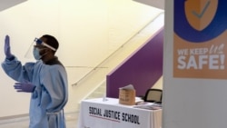 In this Tuesday, Sept. 29, 2020, photo Reginald Galloway, director of operations at The Social Justice Public Charter School, waves goodbye to fifth and sixth grade students after class, in Washington. (AP Photo/Jacquelyn Martin)