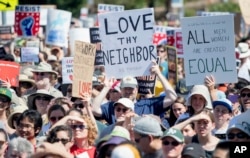 People hold up signs and shout while listening to speakers during a rally against hate in Berkeley, California, Sunday, Aug. 27, 2017.
