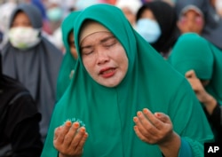 A Muslim woman prays during a special prayer for the victims of earthquake and tsunami at Talise beach in Palu, Central Sulawesi, Indonesia, Oct. 5, 2018.