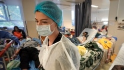 FILE - A member of the medical staff walks in a crowded COVID-19 isolation room at the University Emergency Hospital in Bucharest, Romania, Oct. 22, 2021.