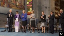 Burmese opposition leader Aung San Suu Kyi, on the podium, second from left, receives standing ovations the Norwegian Nobel Committee her speech at the Peace Nobel Prize lecture at the city hall in Oslo, Saturday, June 16, 2012.