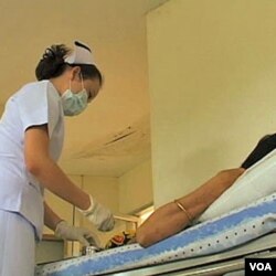 Seorang perawat di Thailand memberika obat anti-retrovirus kepada seorang pasien HIV.