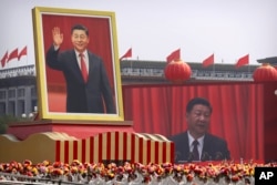 FILE - Participants cheer beneath a large portrait of Chinese President Xi Jinping during a parade to commemorate the 70th anniversary of the founding of Communist China in Beijing, Tuesday, Oct. 1, 2019.