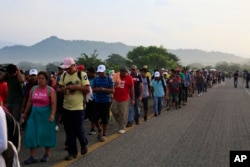 Migrants walk along the road after Mexico's federal police briefly blocked the highway in an attempt to stop a thousands-strong caravan of Central American migrants from advancing, outside the town of Arriaga, Mexico, Oct. 27, 2018.