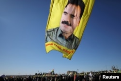FILE - A banner with a picture of imprisoned Kurdish rebel leader Abdullah Ocalan is seen during a protest in Qamishli, Syria, Jan. 30, 2018.