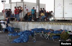 Migrants, who have been picked up within Austria near the border with Hungary, wait at a makeshift camp in Nickelsdorf, Austria, Aug. 29, 2015.