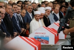 A guard secures Turkish President Recep Tayyip Erdogan (L) with his machine gun during a funeral service for a victim of the thwarted coup in Istanbul at Fatih mosque in Istanbul, Turkey, July 17, 2016.