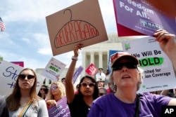 Gracie Burke, 19, center, a student at American University, joins other in a protest against abortion bans, May 21, 2019, outside the Supreme Court in Washington.