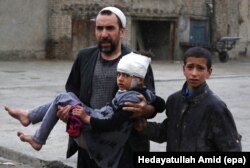 An Afghan man carries a girl who was injured in a suicide bomb blast that targeted the premises of the Ministry of Defense, in Kabul, Afghanistan, 19 April 2016.