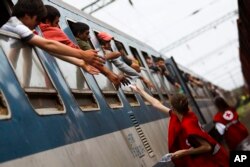 FILE - Activists of the Hungarian Red Cross give water to migrants who arrived by train from Tovarnik, Croatia at the railway station in Zakany, 230 kms southwest of Budapest, Hungary, Tuesday, Sept. 22, 2015.