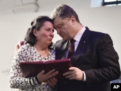 President Poroshenko presents a Hero of Ukraine award to a relative of an activist killed a year ago during mass protests, at the award ceremony in Kyiv, Feb. 20, 2015.