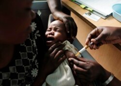 Seorang ibu menggendong bayinya yang menerima vaksin malaria baru sebagai bagian dari percobaan di Pusat Penelitian Proyek Walter Reed di Kombewa di Kenya Barat. (Foto: AP)