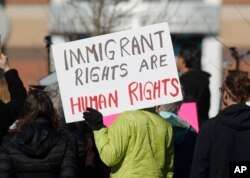FILE - A supporter holds up a placard during a rally outside the Immigration and Customs Enforcement office in Centennial, Colorado, Feb. 15, 2017.