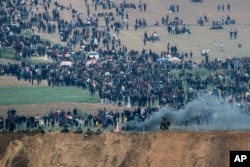 Israeli soldiers stand as Palestinian protesters gather on the Israel Gaza border, Friday, March 30, 2018.