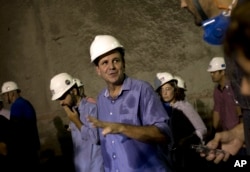 FILE - Rio de Janeiro's Mayor Eduardo Paes, center, talks with the media inside the Expressway Tunnel in Rio de Janeiro, Brazil, March 24, 2015.