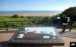 Two visitors look out over Omaha Beach from the Colleville American military cemetery in Colleville-sur-Mer, western France, June 6, 2015.