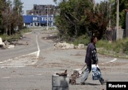 FILE - A man with a cart walks in a street in rebel-controlled Donetsk, Ukraine, July 18, 2015.