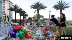 A woman throws a bouquet of flowers at a memorial for the victims of the shooting at the Pulse gay nightclub in Orlando, Florida, June 14, 2016.