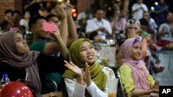 People at a restaurant applaud as they watch TV showing former strongman Mahathir Mohamad sworn in as the new Malaysian Prime Minister in Kuala Lumpur, Malaysia on Thursday, May 10, 2018. (AP Photo/Aaron Favila)