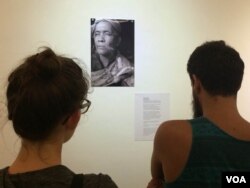 Visitors take a closer look at another fortune teller, Seim Chantha, holding three smoked cigarettes in his hand.