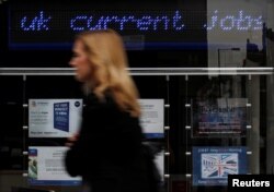FILE - A pedestrian walks past an employment center in London.