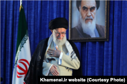 FILE - Iranian Supreme Leader Ayatollah Ali Khamenei gestures to a crowd at a June 4, 2019 ceremony in Tehran marking the 30th anniversary of the death of his predecessor, Ayatollah Ruhollah Khomeini, whose portrait appears behind him.