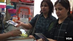 Poonam Sharma, right, looks at masks which many city residents have been purchasing in recent days. (A. Pasricha/VOA)