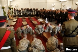 FILE - Armed Forces of Malta soldiers lay down coffins with the bodies of migrants at an interfaith burial service at Mater Dei Hospital in Tal-Qroqq, outside Valletta, April 23, 2015.
