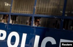 FILE - Defendants look out from a police truck as they arrive at a district court, in Yangon, Myanmar, Dec. 15, 2017.