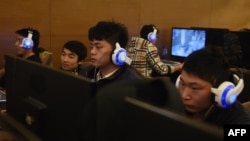 FILE - Young men sit at computers at an internet cafe in Beijing, China, Dec. 16, 2015.
