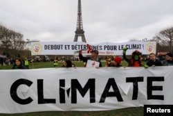 Environmentalists hold a banner that reads "Standing and Determined for the Climate" at a climate conference protest demonstration near the Eiffel Tower in Paris, France, Dec. 12, 2015.